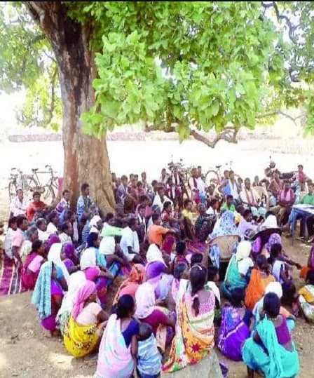 पेड़ के नीचे ग्राम सभा में एकत्र ग्रामीण, अधिकतर महिलाएँ